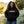 Woman wearing black hoodie with 'Stono Rebellion 1739 Afrikan Diaspora' print, celebrating African heritage outdoors.